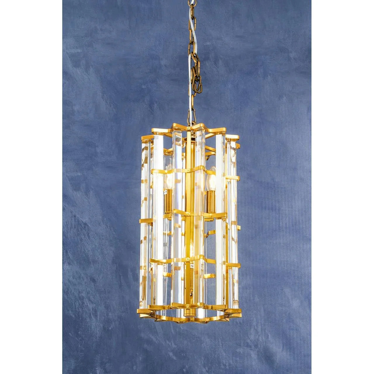 Gold and glass hanging pendant light with geometric frame against blue wall