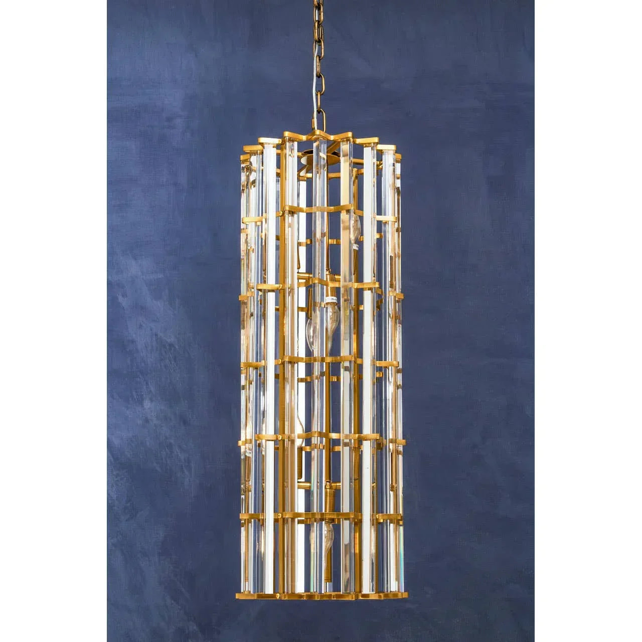 Gold and glass pendant light fixture with cylindrical design against navy wall