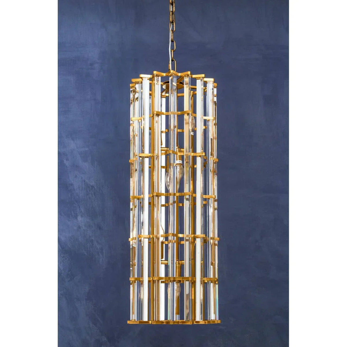 Gold and glass pendant light fixture with cylindrical design against navy wall
