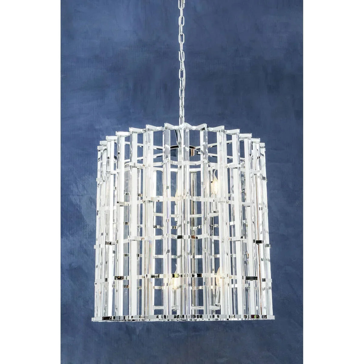 Modern crystal pendant light with geometric frame and chrome finish against blue wall