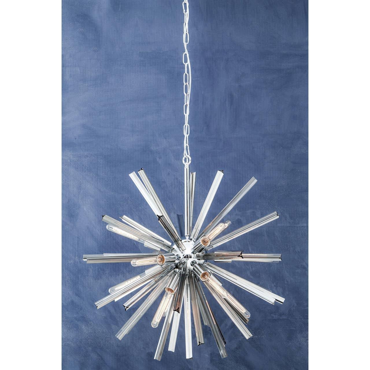 Modern chrome and glass chandelier with starburst design hanging against blue wall
