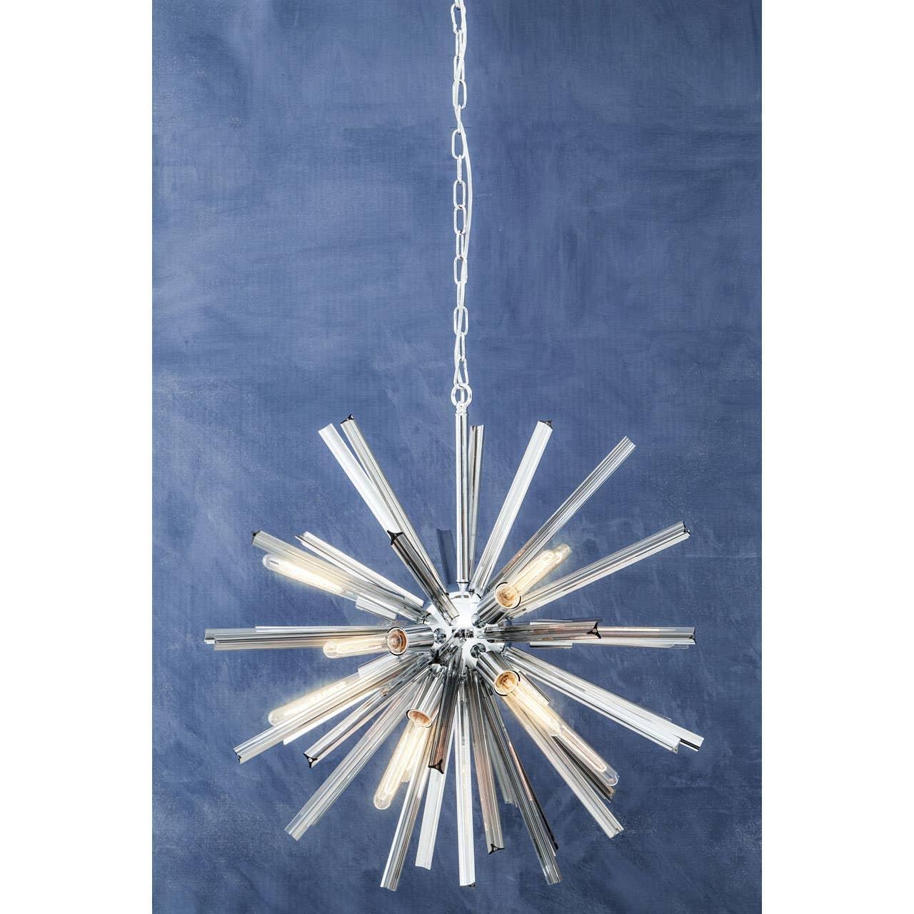 Modern starburst chandelier with chrome finish and exposed bulbs against blue wall