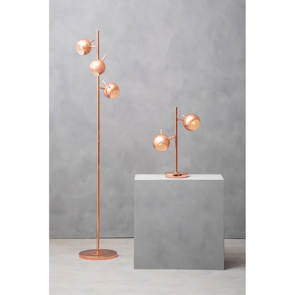 Copper finish floor lamp and matching table lamp with globe shades on grey background