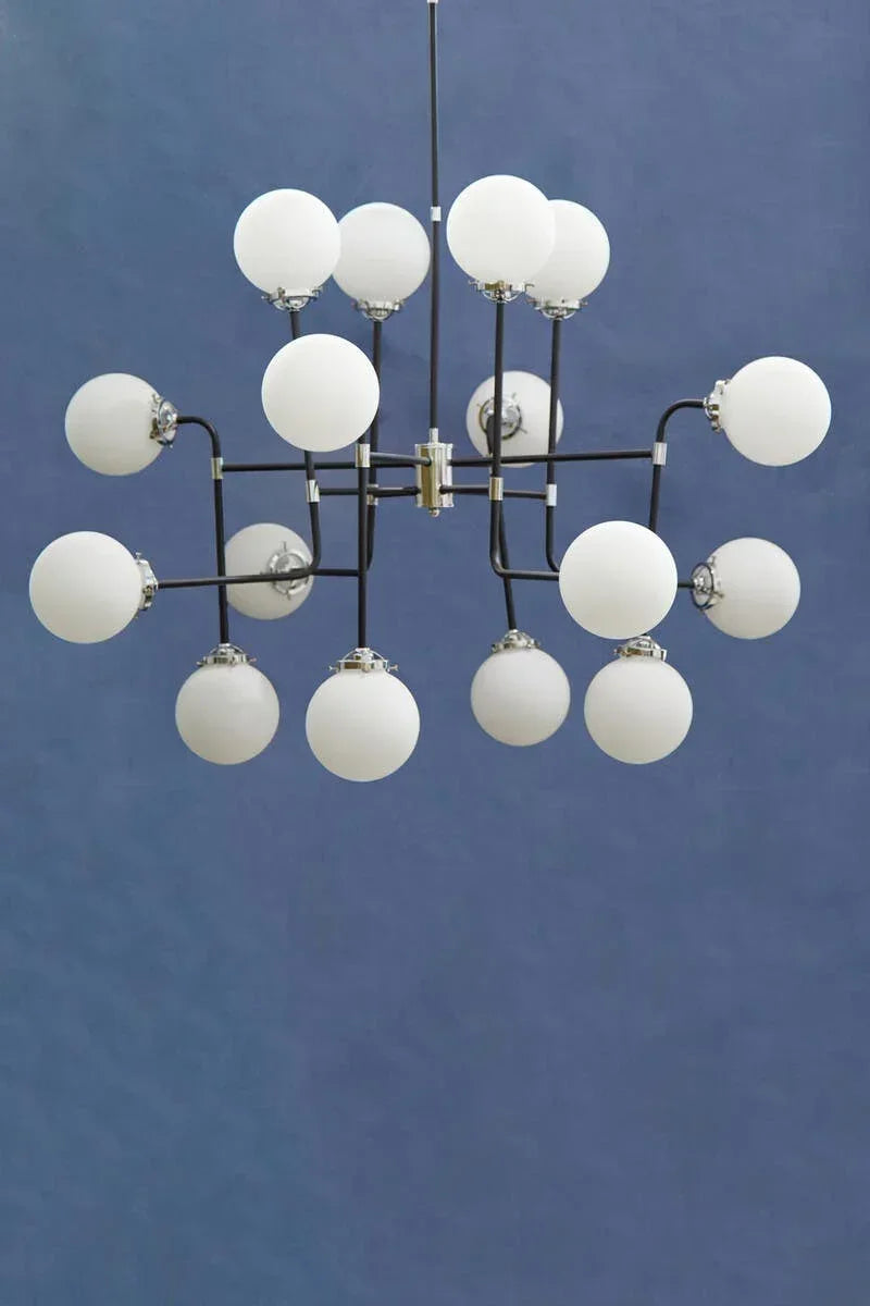 Modern black chandelier with white globe lights against a blue wall