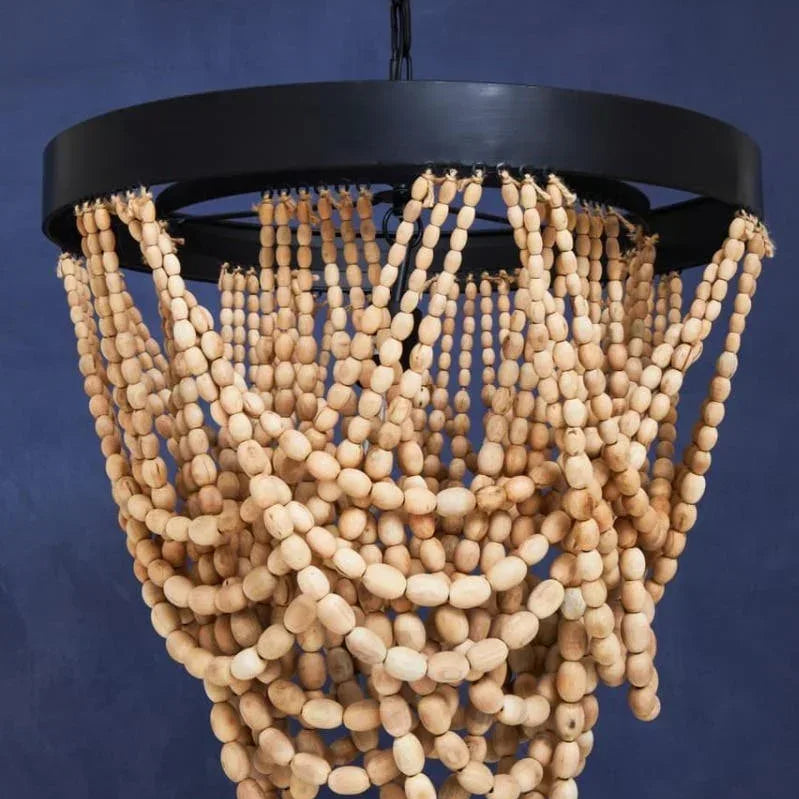 Boho wood bead chandelier with round black frame hanging against dark blue wall