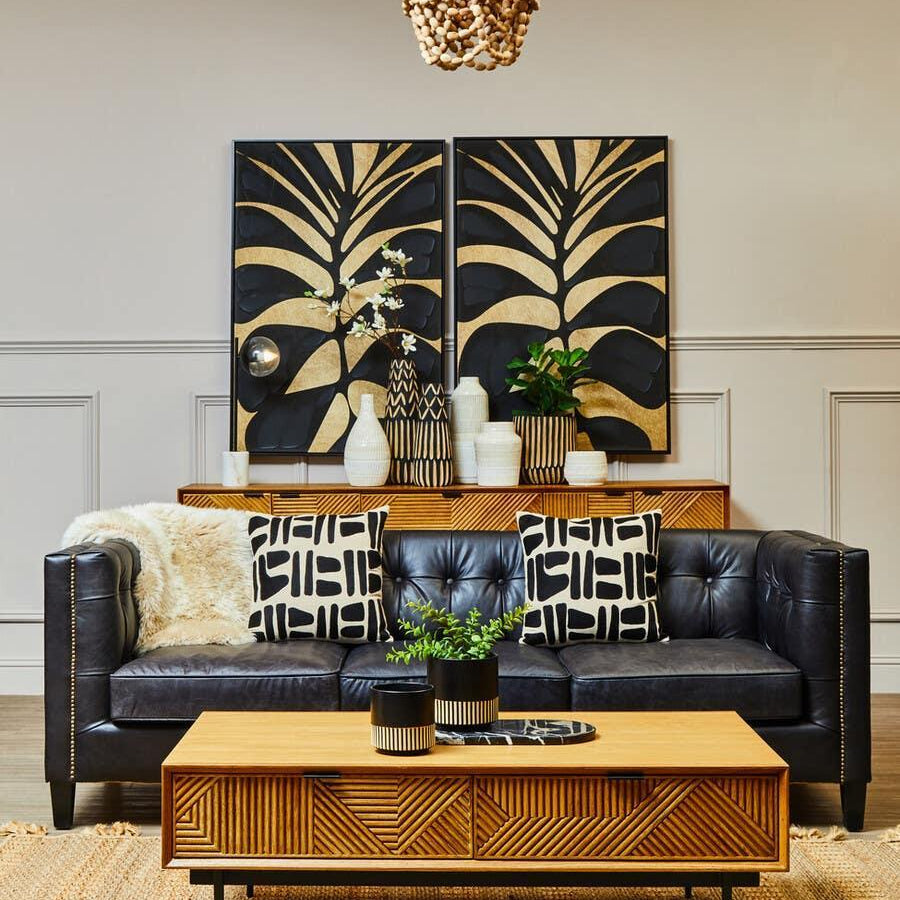 Black leather sofa with geometric cushions and wooden coffee table in modern living room