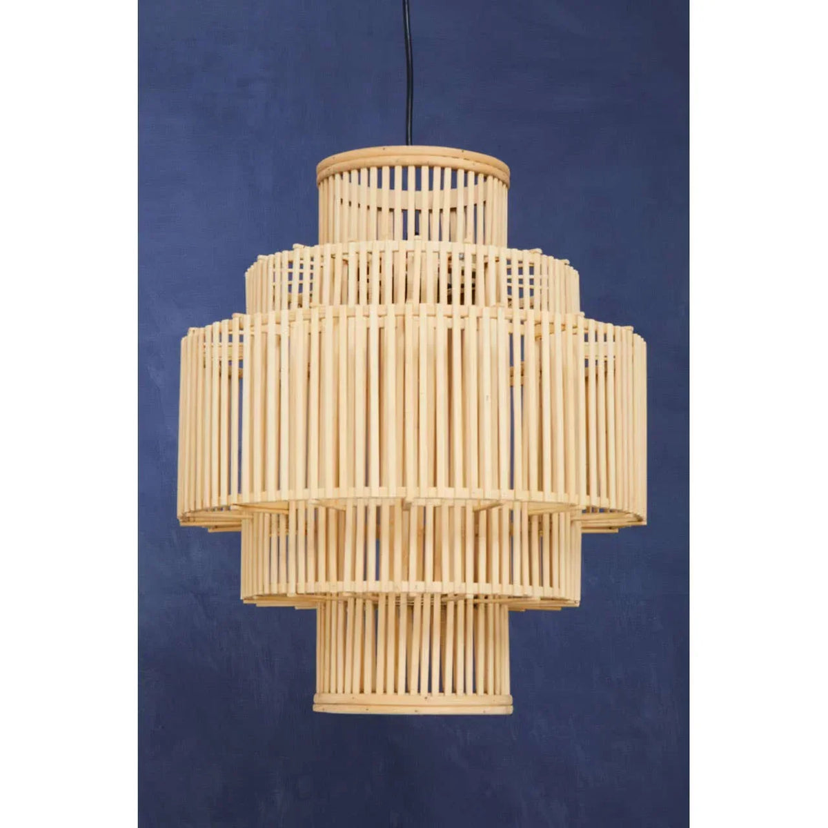 Natural bamboo pendant light with tiered cylindrical design against navy wall
