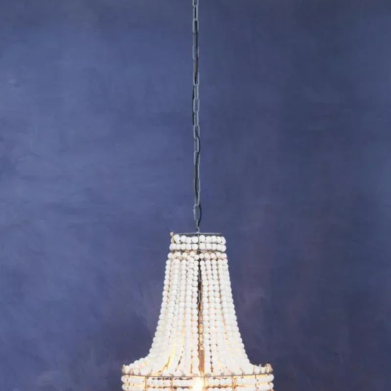 Beaded chandelier with white wooden beads and metal frame hanging against a blue wall