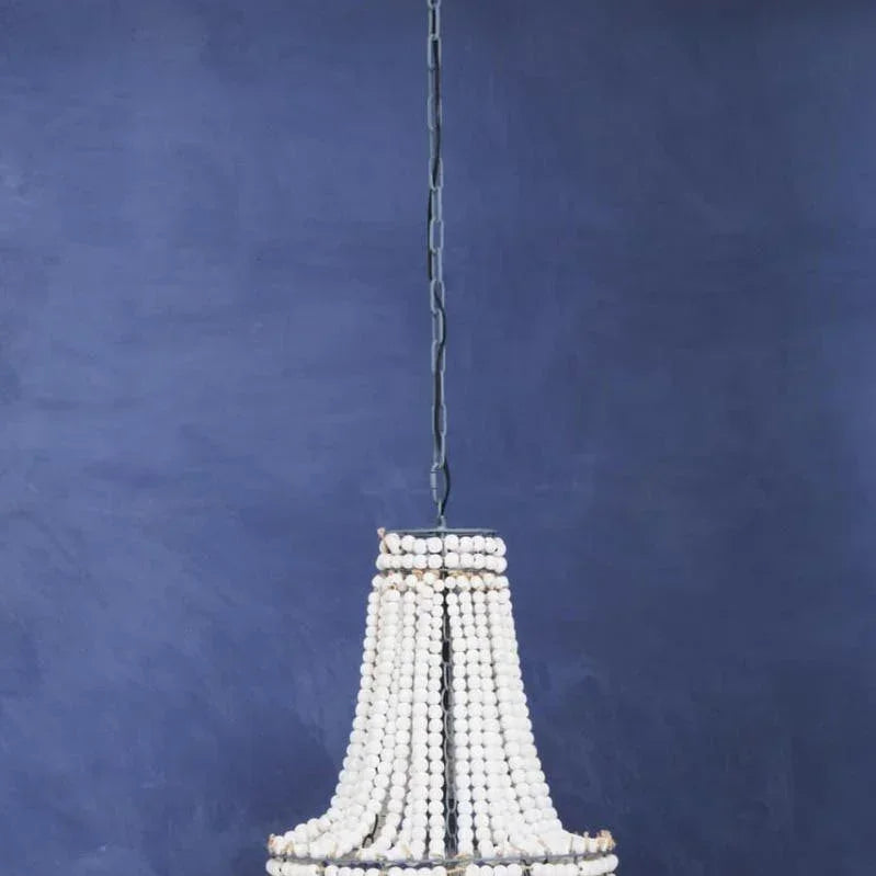 White beaded chandelier with metal frame hanging against a deep blue wall