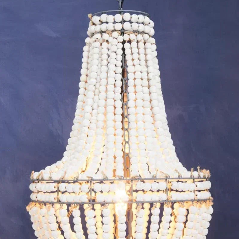 White beaded chandelier lighting with tiered design and metal frame against a blue wall