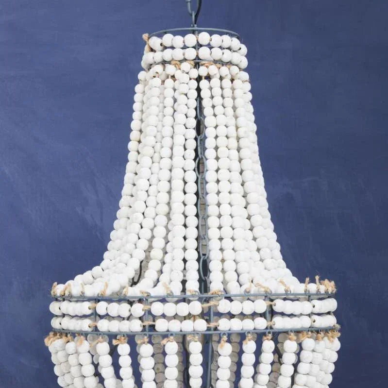White beaded chandelier light fixture against a blue background, boho style home decor