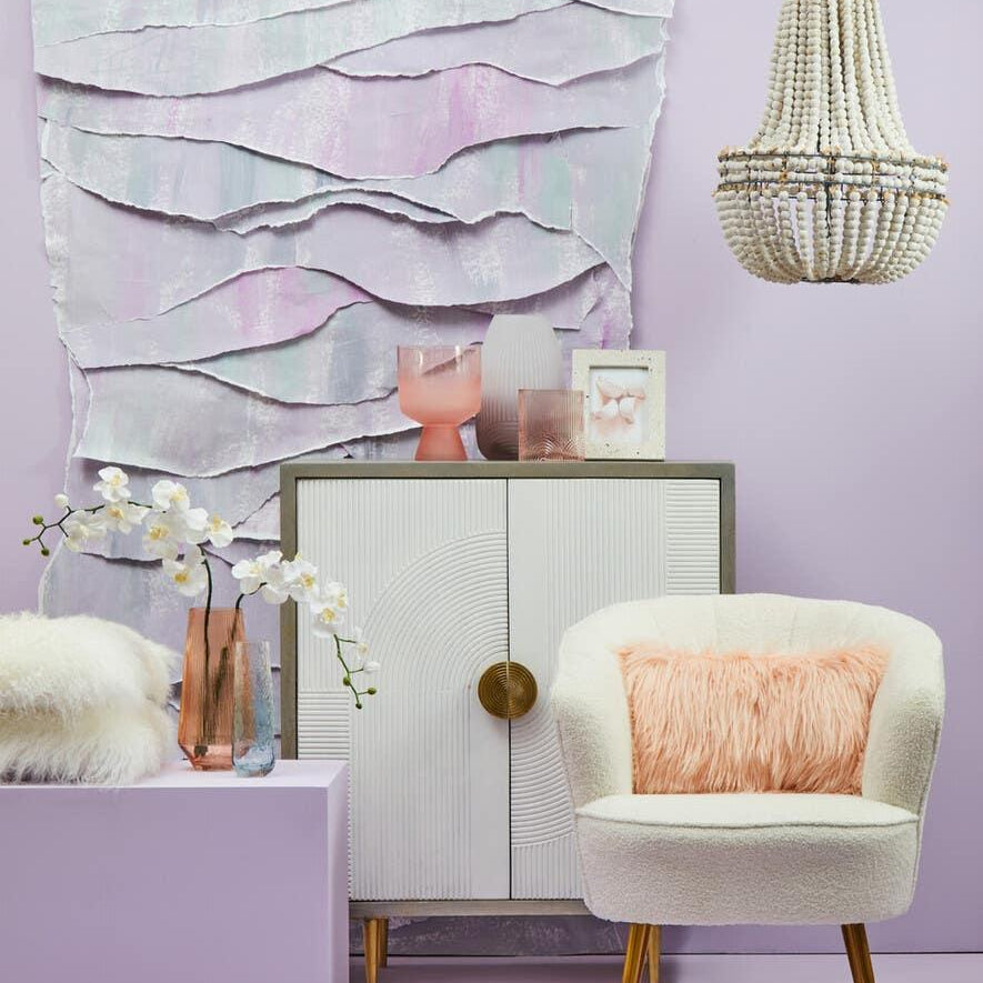 Cream accent chair with pink faux fur cushion, white sideboard, modern beaded chandelier