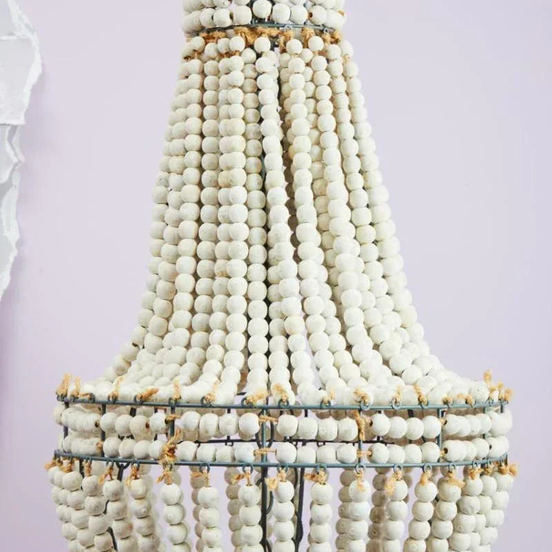 White beaded chandelier light fixture with layered strands on metal frame, close-up