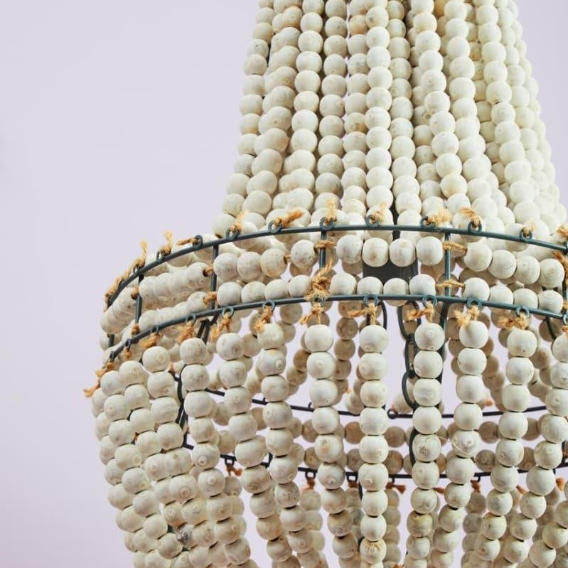 White wooden bead chandelier with tiered design and rope detail against a light background