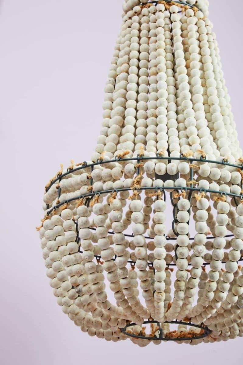 White wooden bead chandelier with tiered design and rope detail against a light background