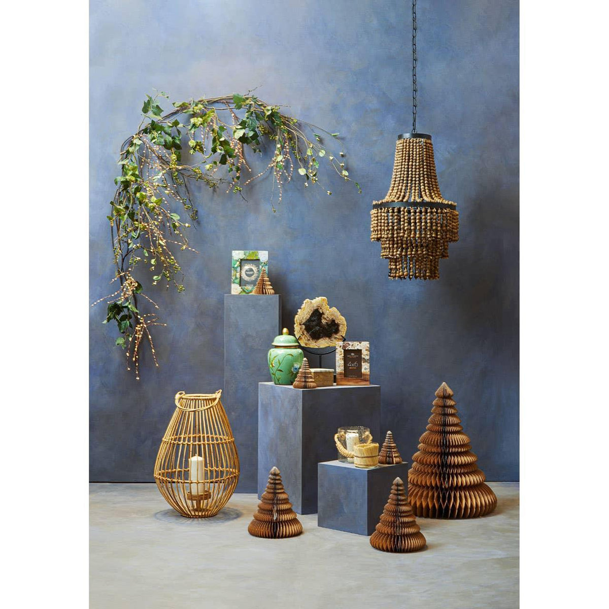 Wood bead chandelier and wicker decor with candle lantern and green ceramic jar on display plinths