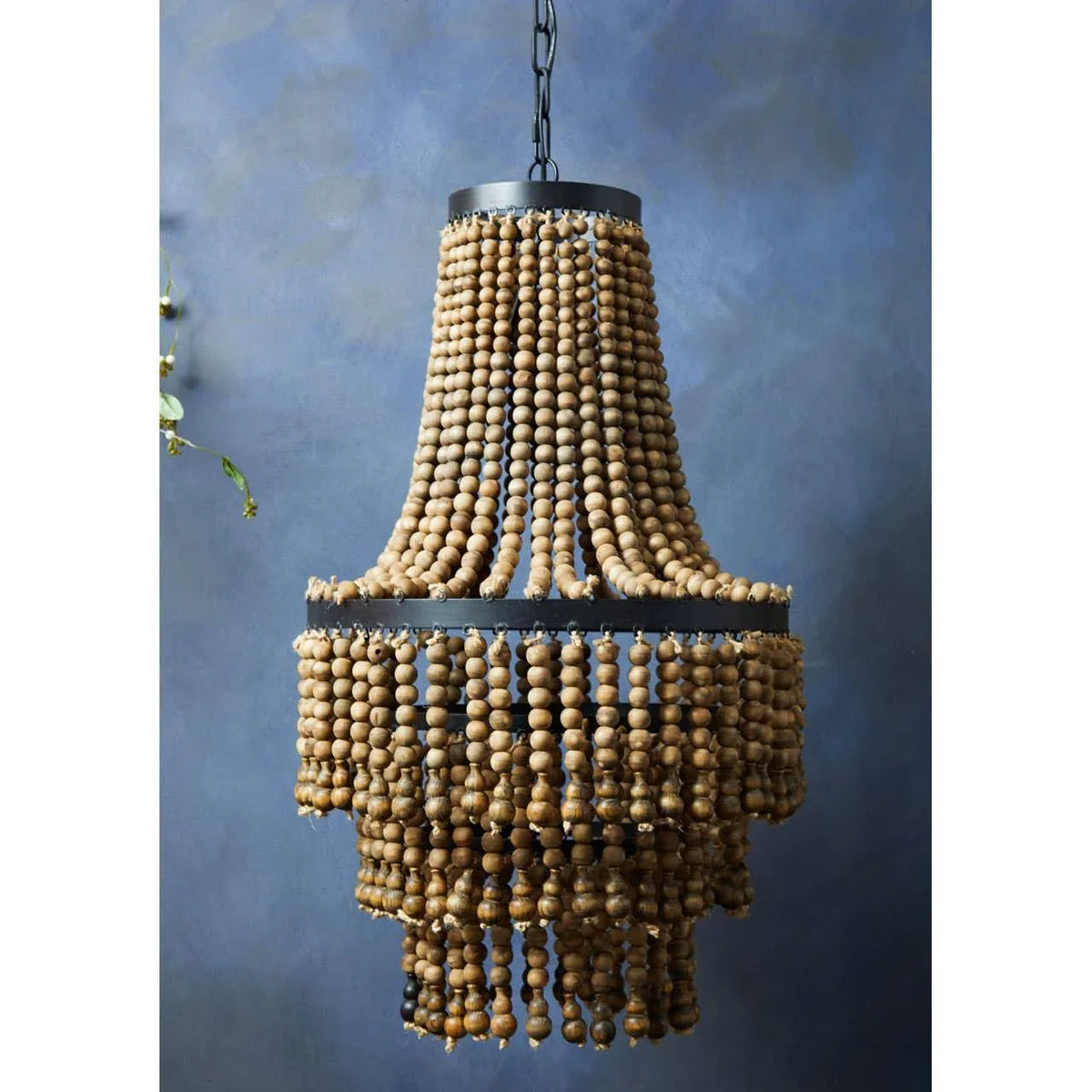 Wood bead chandelier with tiered strands hanging against a blue wall