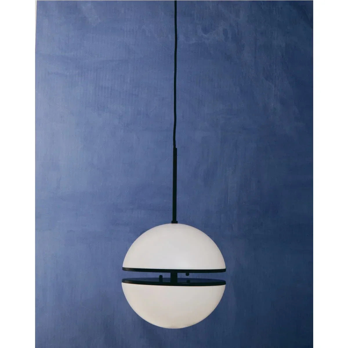 Modern globe pendant light with black trim against a blue textured wall