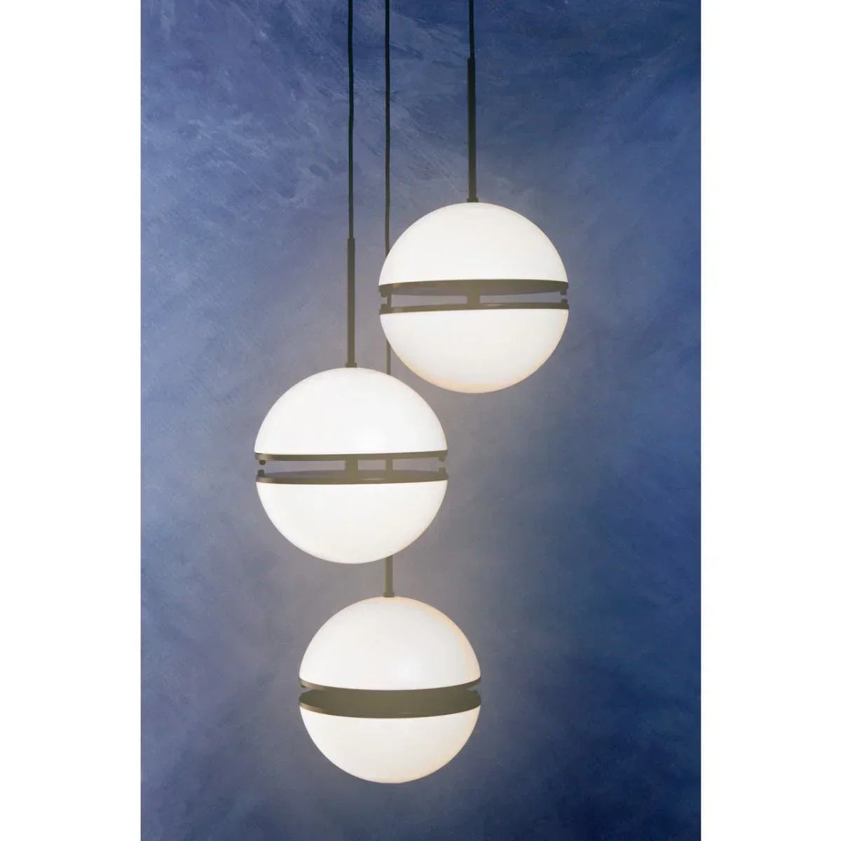Modern pendant lights with white glass globes and black bands hanging against blue wall