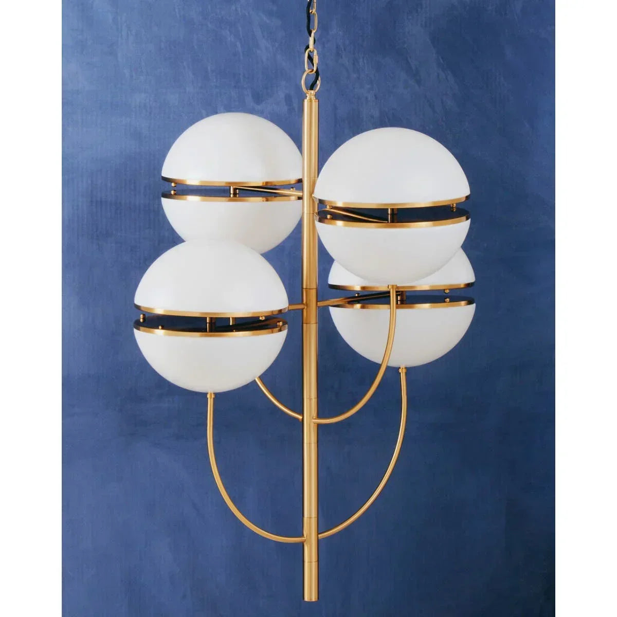 Modern gold chandelier with four white globe lights against blue wall