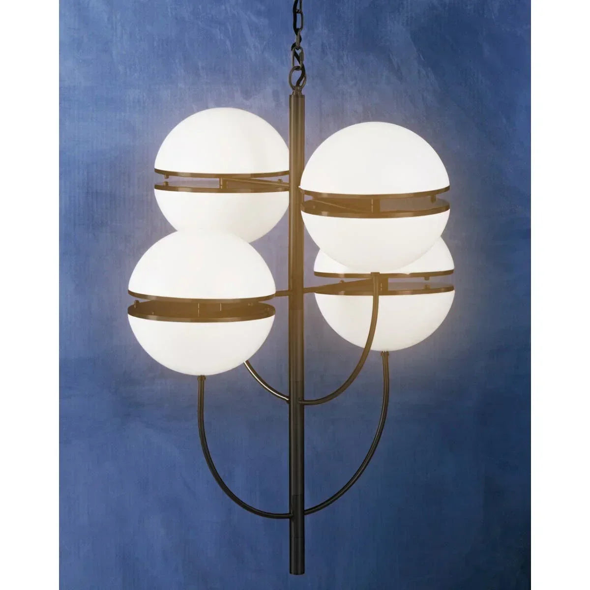 Modern black metal chandelier with four round white glass shades against blue wall