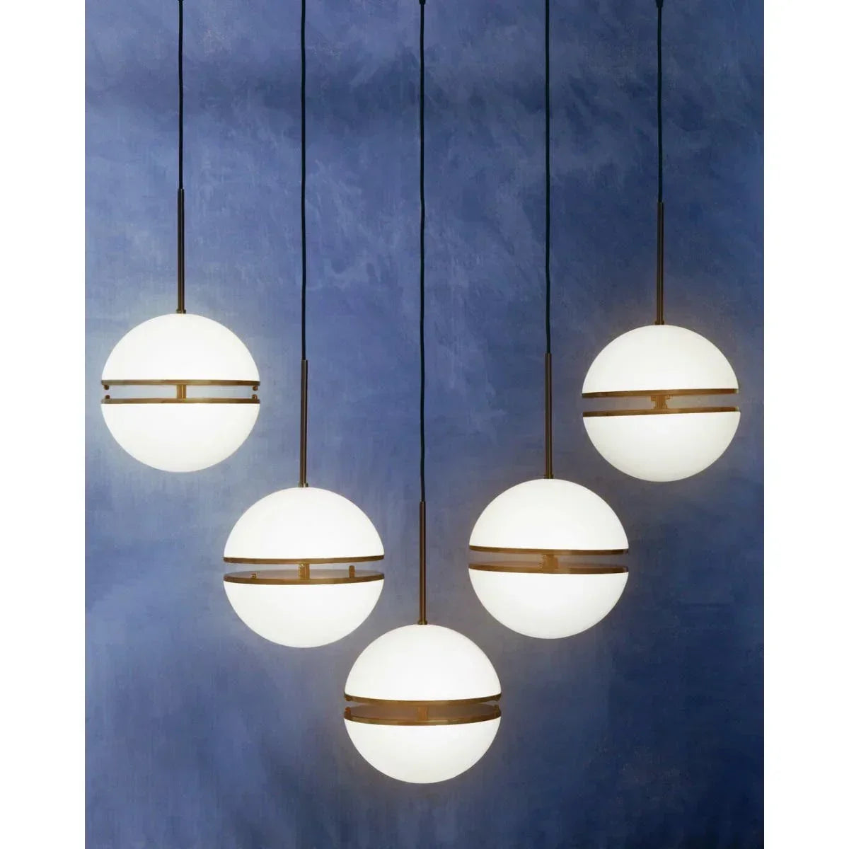 Modern globe pendant lights with brass detailing against a blue wall