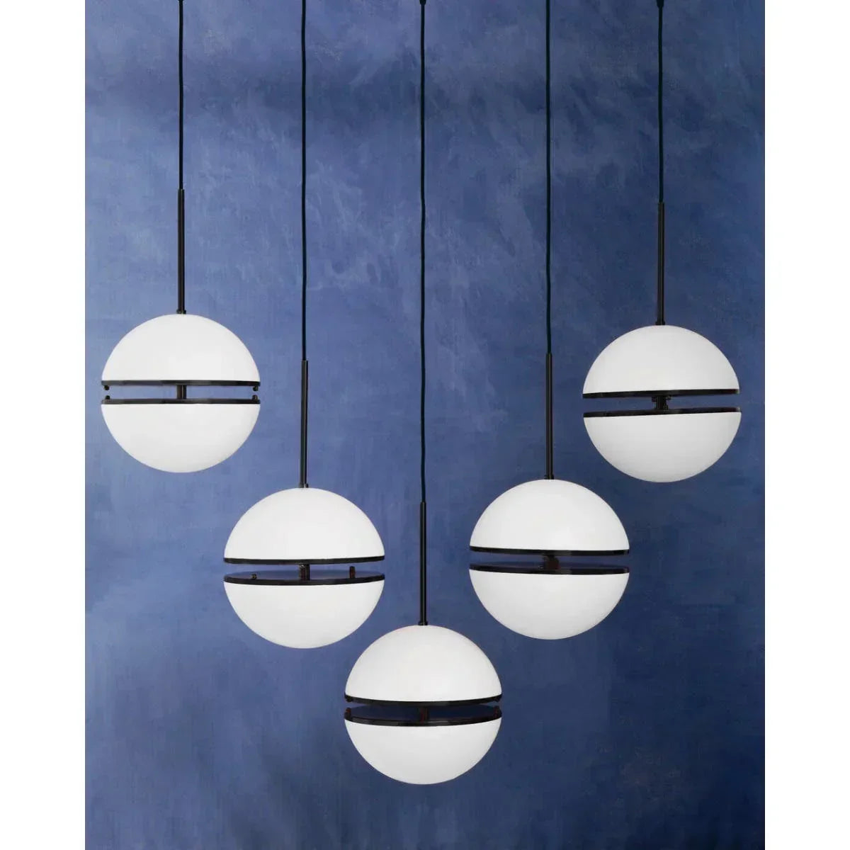 Cluster of five modern globe pendant lights with black accents against blue wall