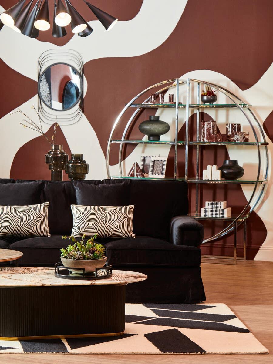 Black velvet sofa with geometric cushions and coffee table in modern living room setting