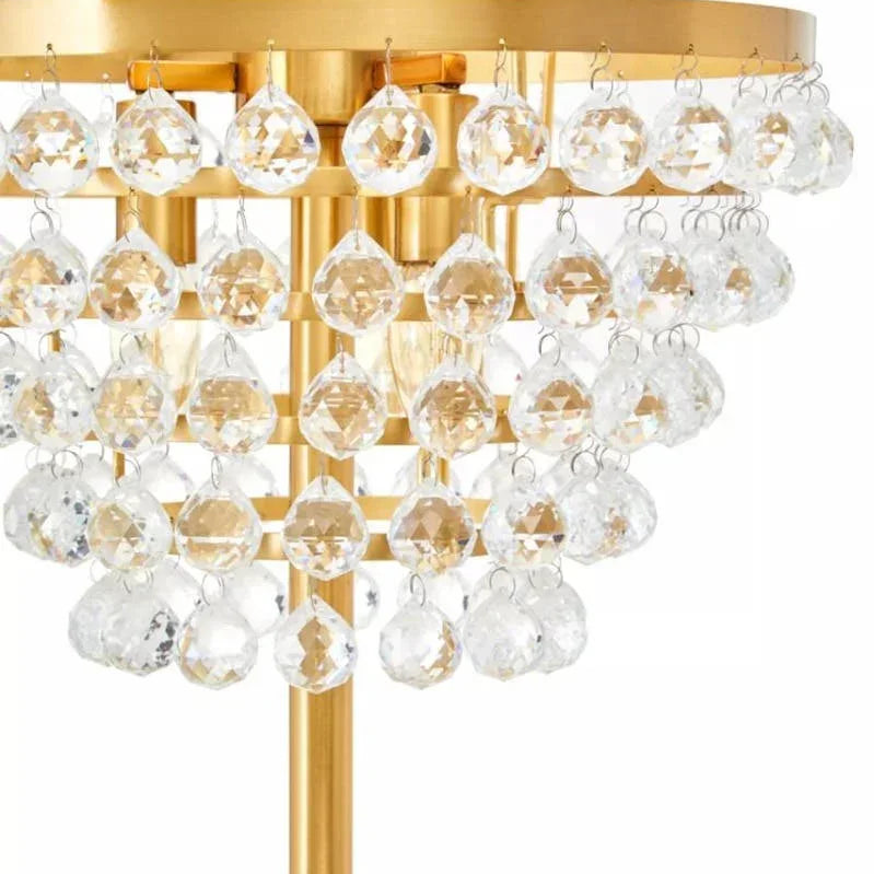 Gold table lamp with two-tiered clear crystal drops and metal base, close-up view