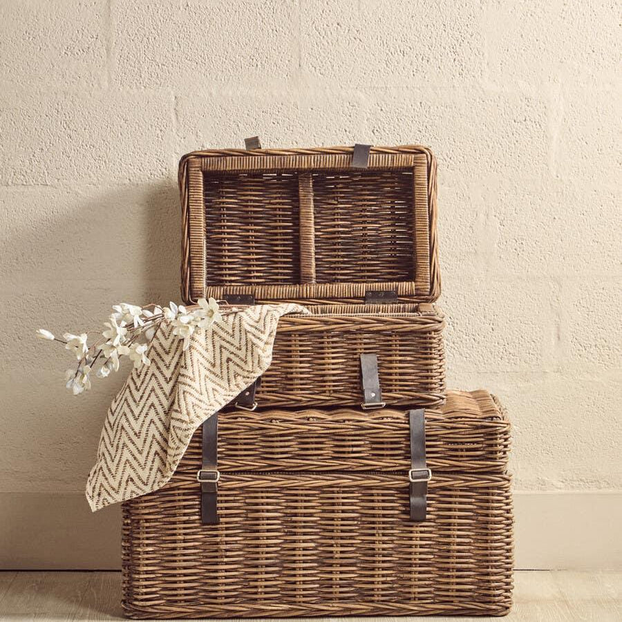 Set of three wicker storage baskets with leather straps, throw blanket and flowers