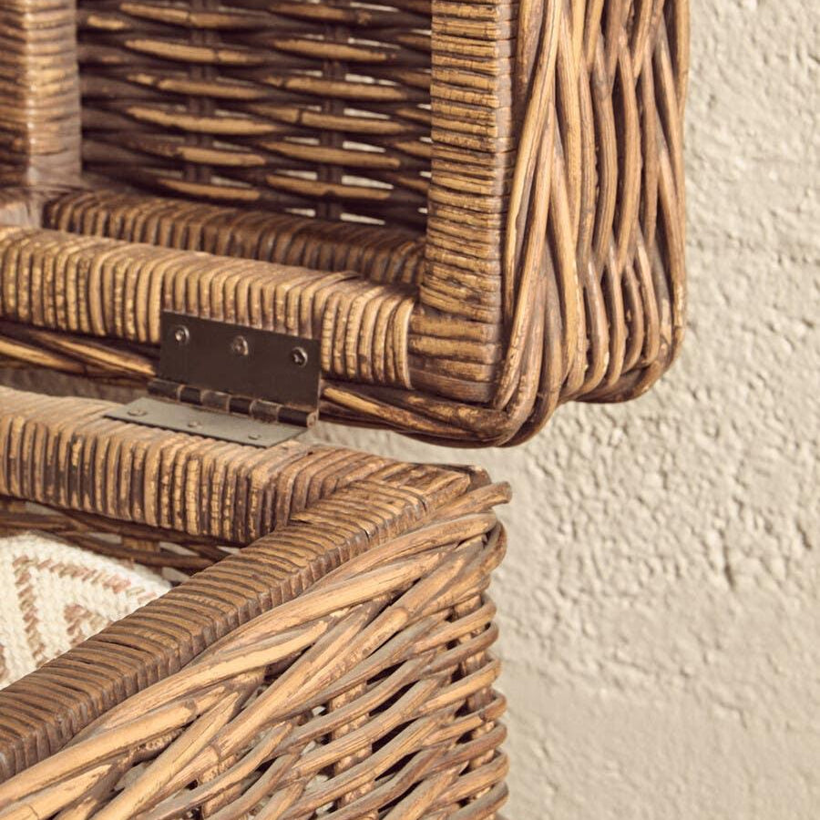 Closeup of open wicker storage basket with hinged lid against textured wall