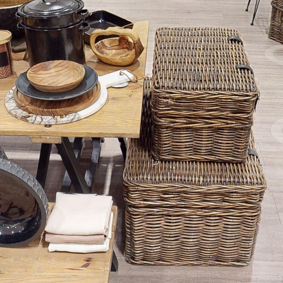 Wicker storage baskets stacked beside wooden dining table with kitchenware