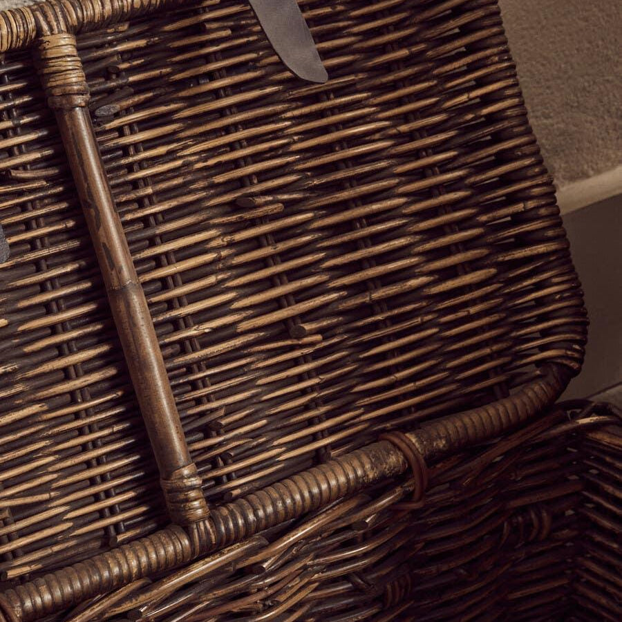 Closeup of open wicker storage basket with leather loop detail on lid