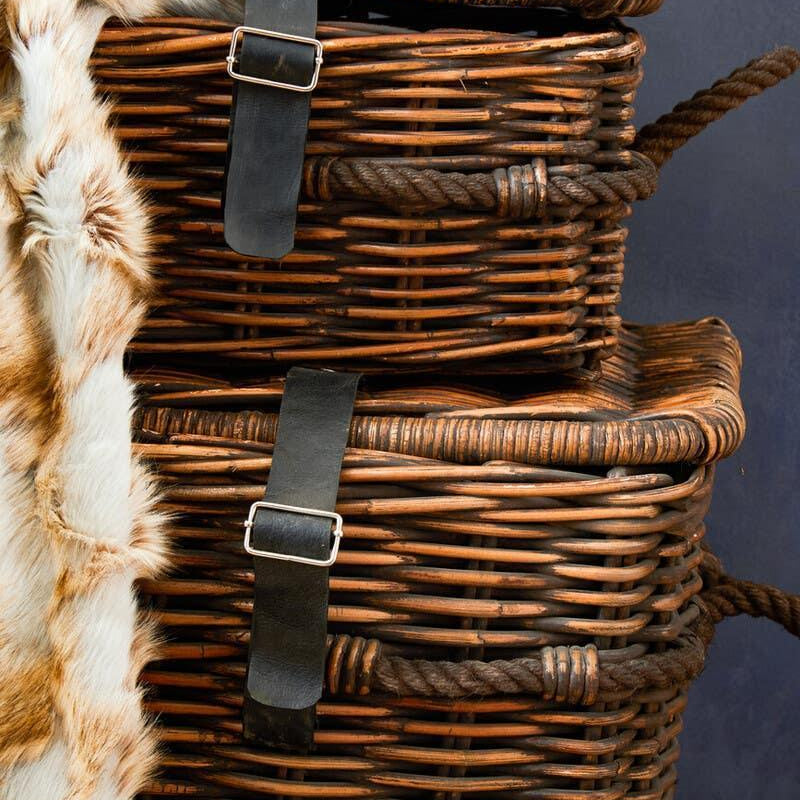 Stacked wicker storage baskets with rope handles and black leather buckle straps