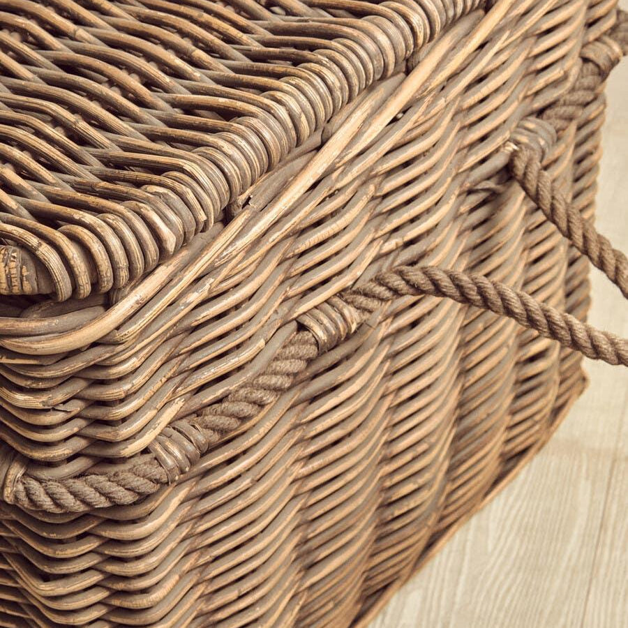 Wicker storage basket with rope handles on wooden floor, close up of woven texture