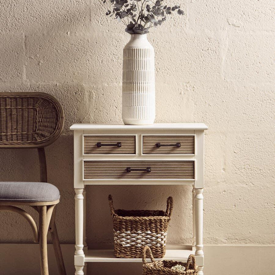 Cream console table with rattan drawers, decorative vase, and woven storage baskets