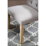 Grey upholstered dining chair with wooden legs, stud detailing, on patterned rug