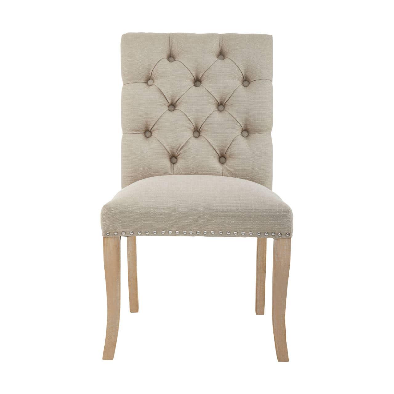 Beige upholstered dining chair with button tufted back and nailhead trim, light wood legs