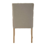 Beige upholstered dining chair rear view with wooden legs and silver stud detailing