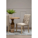 Beige upholstered dining chair with button tufting next to wooden table on patterned rug