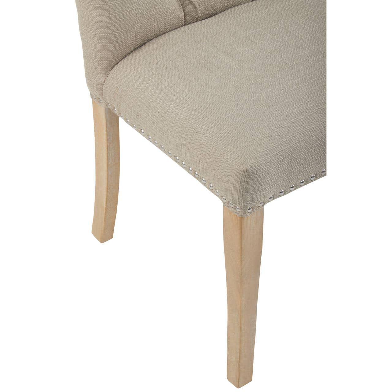 Beige upholstered dining chair with wooden legs and silver stud detailing close-up