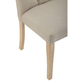 Beige upholstered dining chair with wooden legs and silver stud detailing close-up