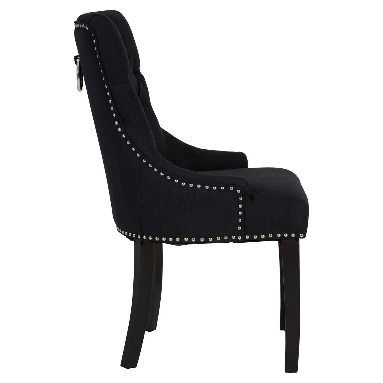 Side angle of black upholstered dining chair with metal stud detailing and dark wooden legs