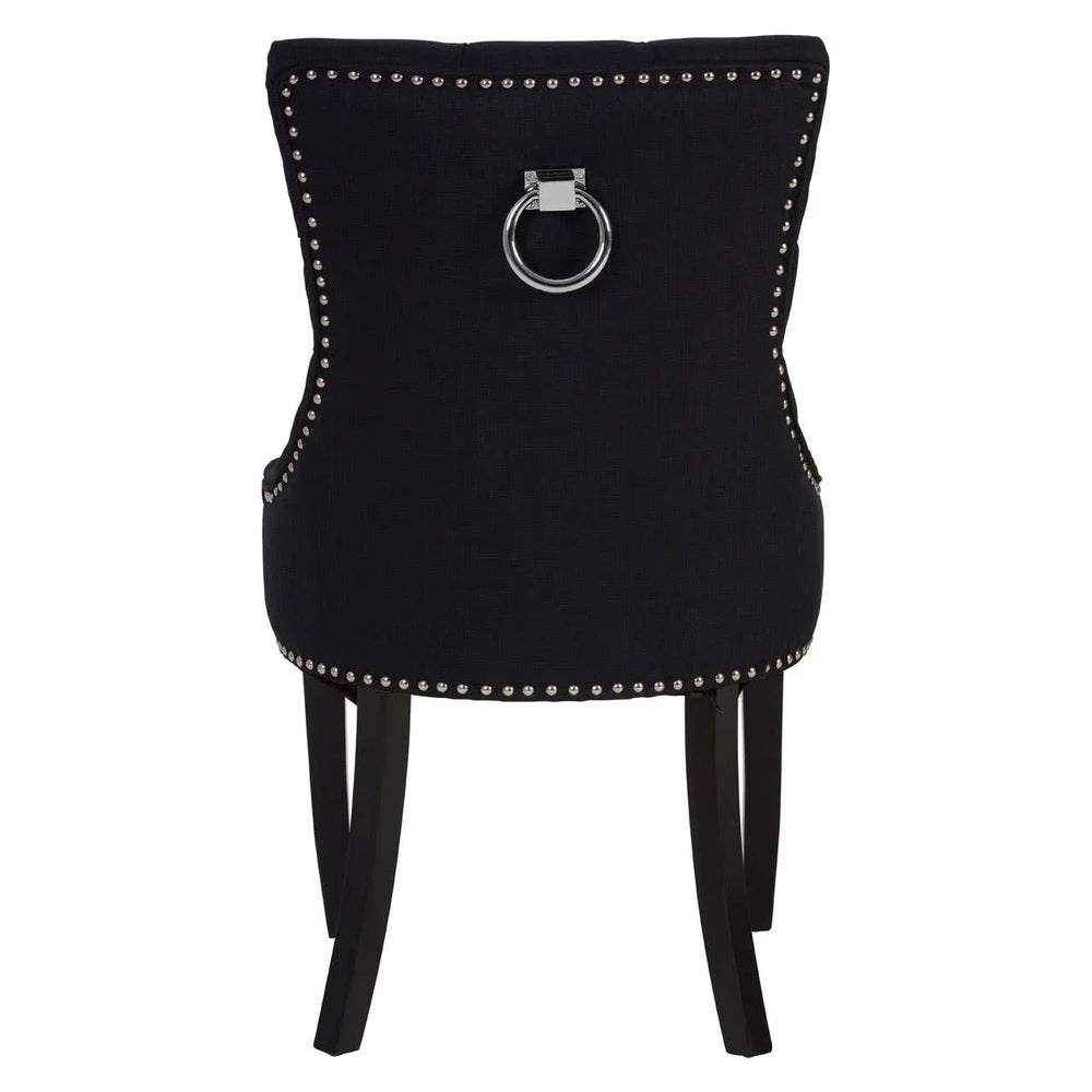 Black dining chair with chrome ring handle, silver stud trim, and dark wooden legs, rear view