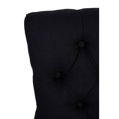 Closeup of black fabric headboard with deep button tufting