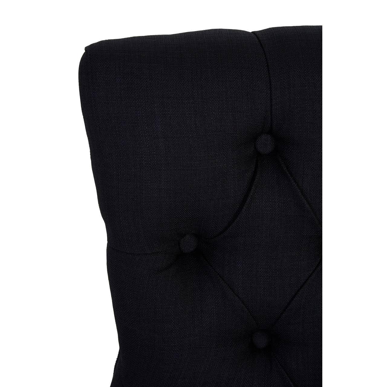 Closeup of black fabric headboard with deep button tufting