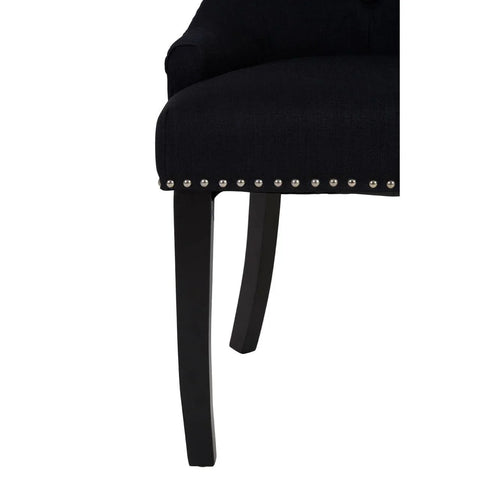 Black fabric dining chair close-up with dark wood legs and silver stud detailing