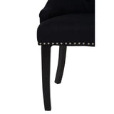 Black fabric dining chair close-up with dark wood legs and silver stud detailing