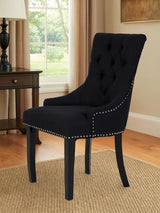 Black upholstered dining chair with button tufted back and silver stud trim on wooden legs