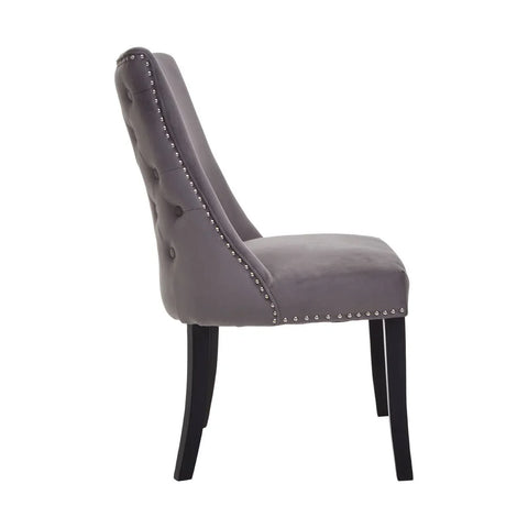 Grey velvet dining chair with button tufted back, silver stud detailing, and black legs side view